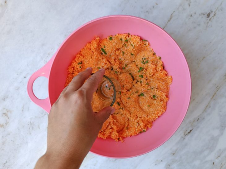 Arroz cozido sendo amassado ainda quente com cheiro-verde.