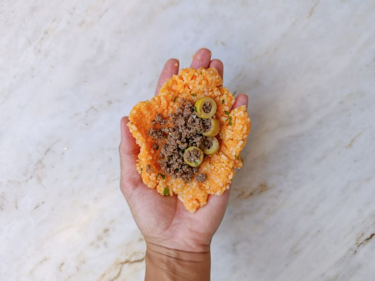 Massa sendo aberta na mão com recheio no centro.