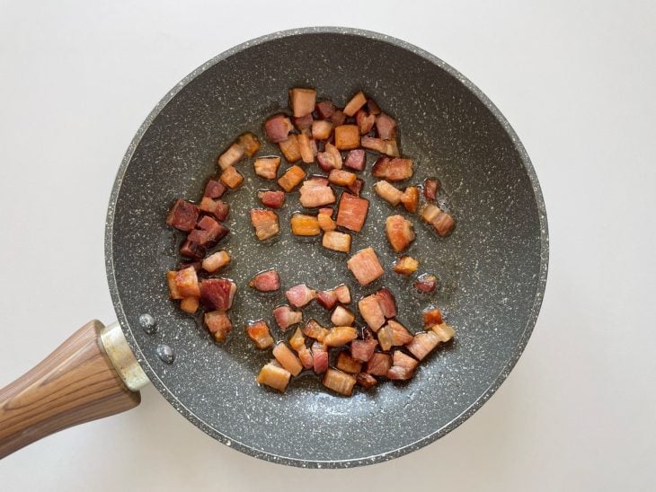 Bacon frito numa frigideira.