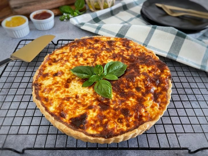 Quiche pronta e decorada com folhas de manjericão.