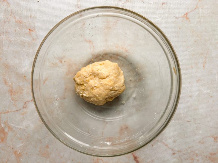 Massa homogênea sendo formada e envolvida em plástico filme.