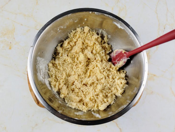 Farinha de trigo, manteiga e parmesão ralado misturados em uma tigela.