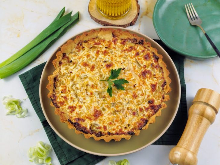 Quiche de alho-poró desenformada sobre um prato pronta para consumo.