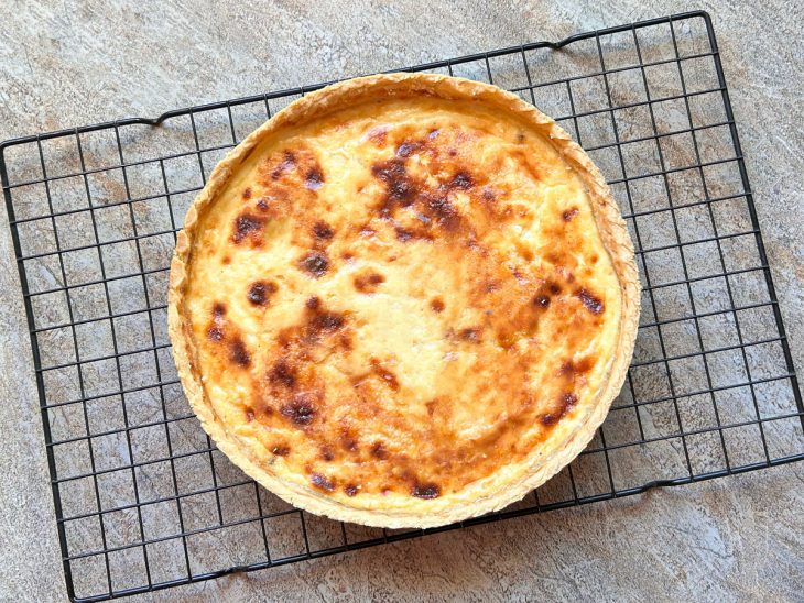 Quiche assada descansando sobre uma grade de cozinha.