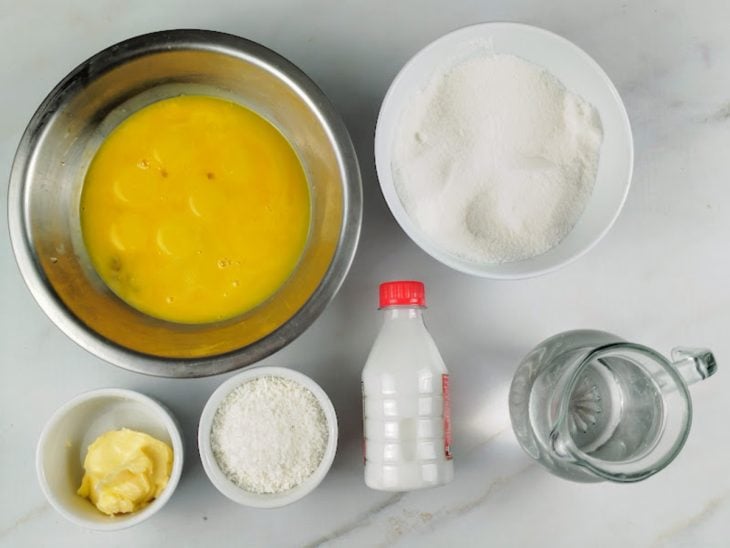 Ingredientes para a receita de quindim simples, reunidos em uma bancada.