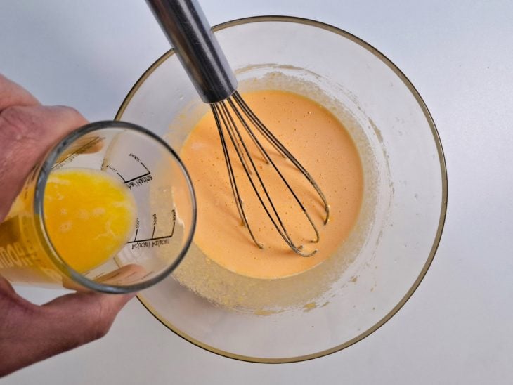 Adição de leite e manteiga na tigela com os outros ingredientes do quindim.