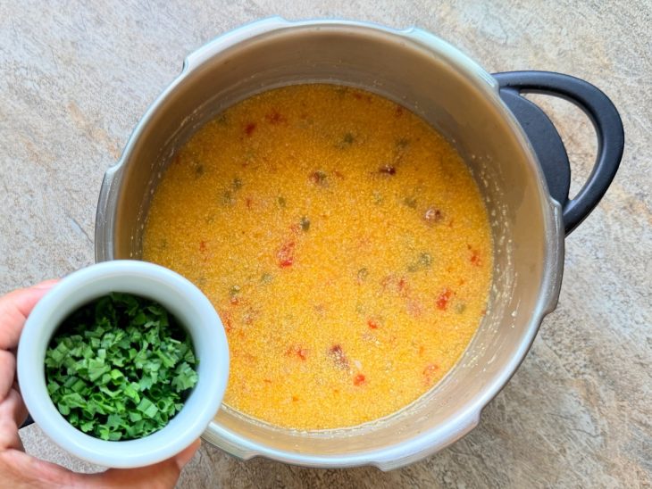Panela aberta, salsinha sendo adicionada.