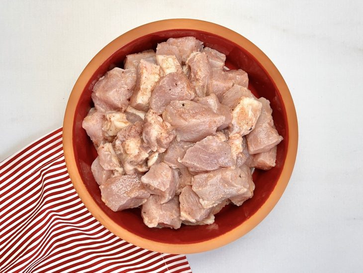 Um recipiente com carne de porco cortada em cubos.