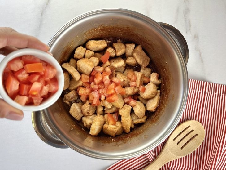 Uma panela com carne de porco e temperos cozinhando.