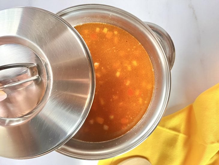 Uma panela com as costelinhas, bacon, calabresa, quirera, água e temperos.
