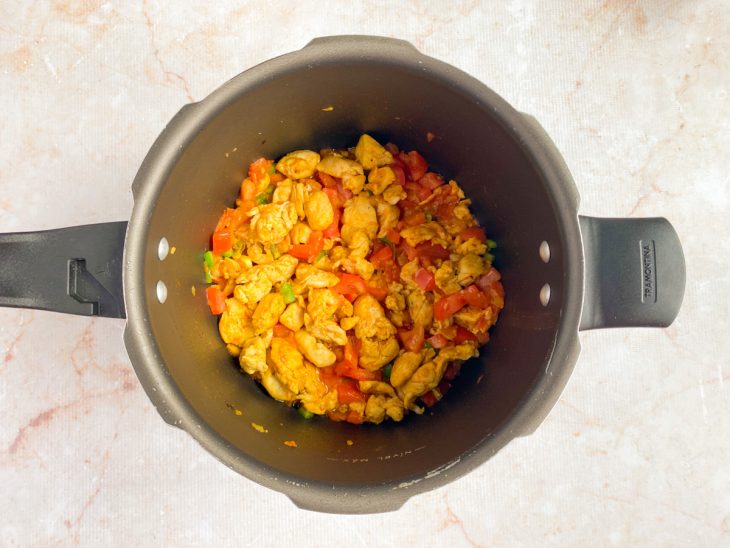 Na panela de pressão, pimentão, tomates e a páprica são adicionados.