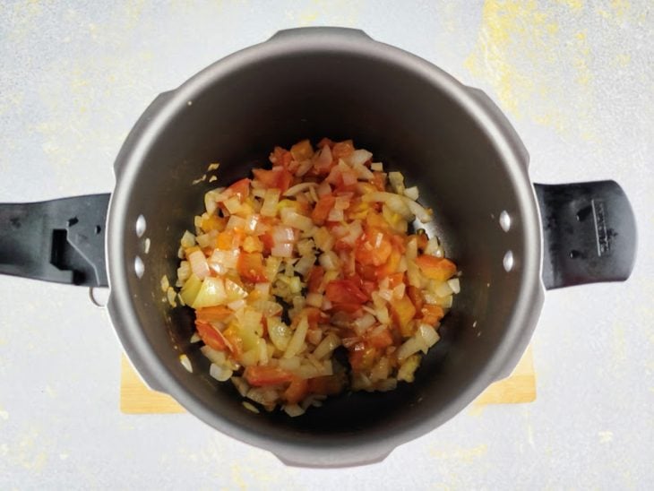 Uma panela com tomate e cebola refogando.