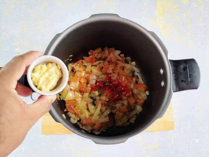 Uma panela com tomate, cebola e temperos refogando.