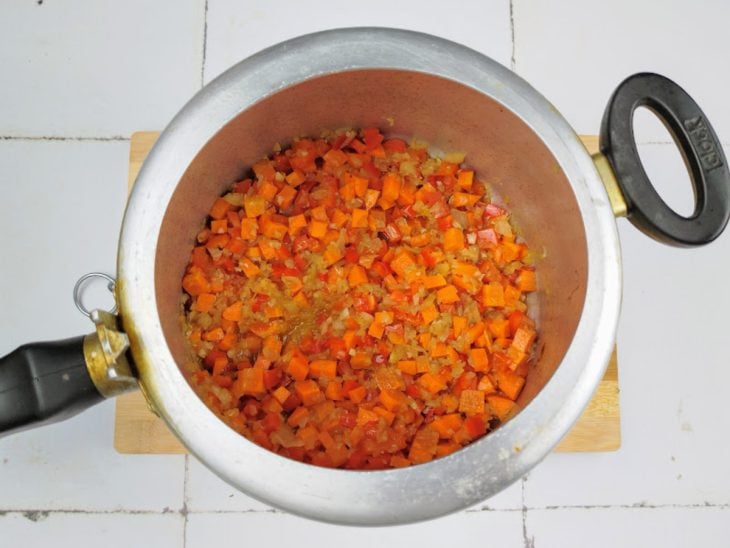 Uma panela com alho, cebola, pimentão, cenoura e pimenta.