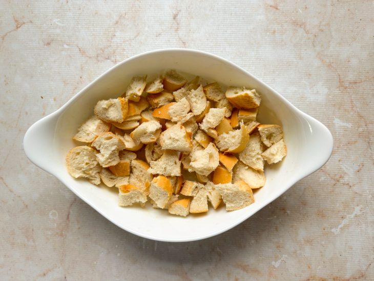 Pães amanhecidos sendo cortados em cubos médios.