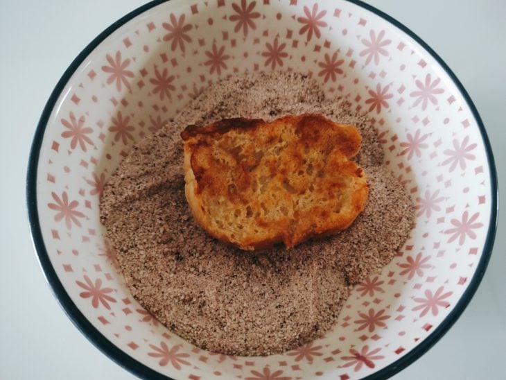 Fatia de rabanada em um pote com açúcar e canela.