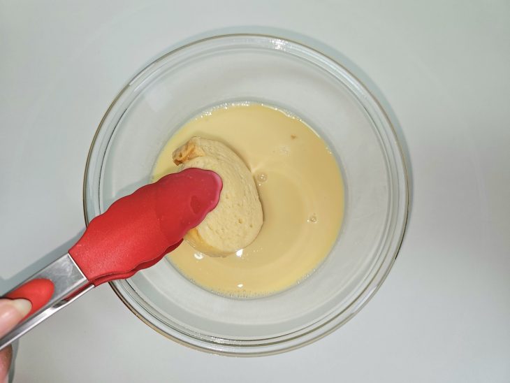 Pães molhados na mistura com o pegador.