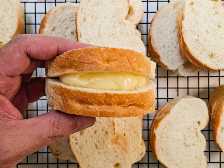 Fatias de pão sendo recheadas com creme e fechadas.
