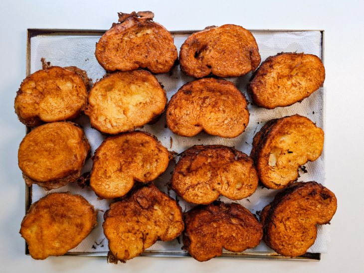 Rabanadas mornas sendo envolvidas na mistura de açúcar e canela.