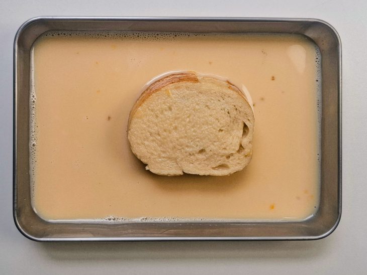 Pão sendo mergulhado na mistura.