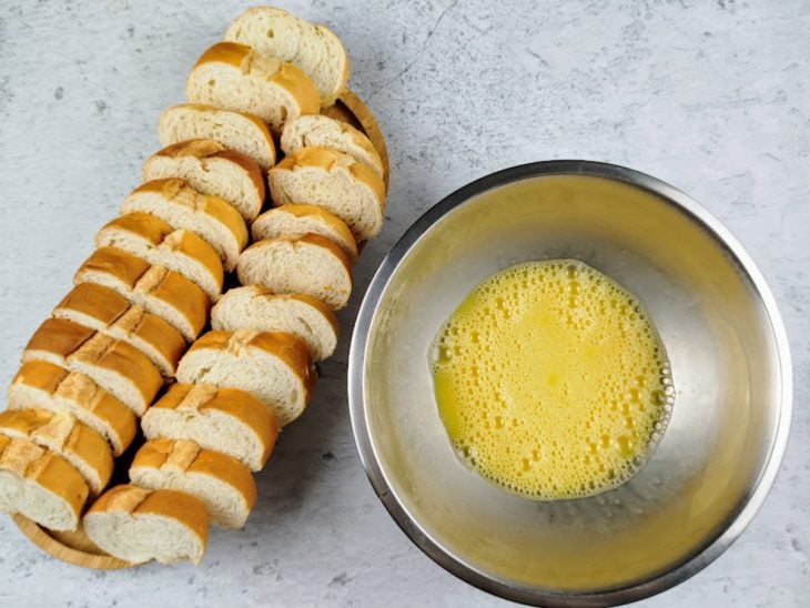 Pãos fatiados e uma tigela com ovos e sal batidos.