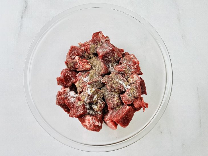 Carne temperada em uma tigela de vidro redonda.