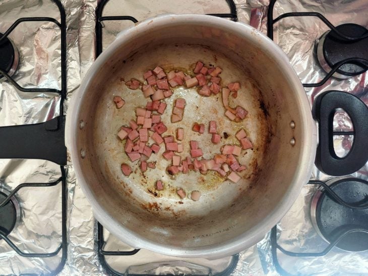 Panela de pressão com cubos de bacon sendo dourados.