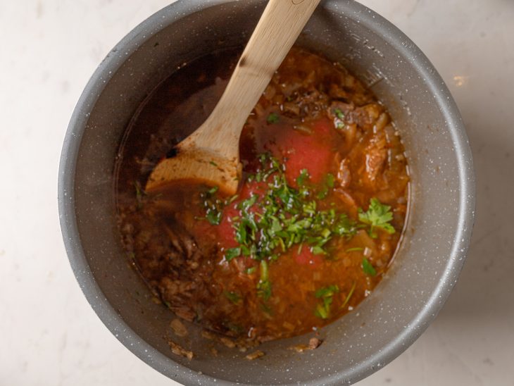 Tomate pelado e salsinha adicionada na panela com a carne.