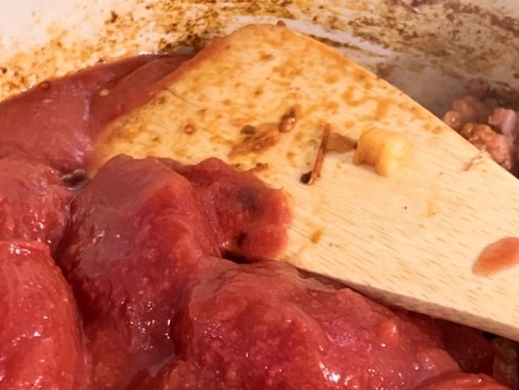 Uma panela com a carne da linguiça com tomates pelados..