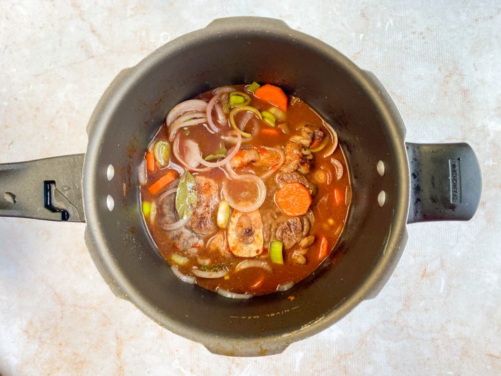 Temperos, extrato de tomate e água adicionados na panela.