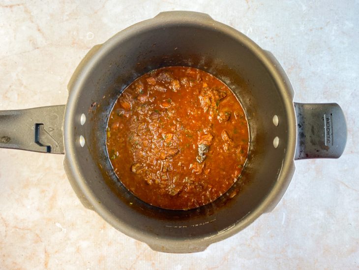 Carne desfiada colocada de volta na panela com molho.