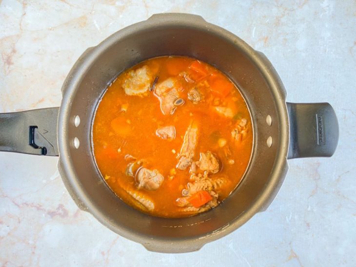 Panela de pressão com caldo e ingredientes.