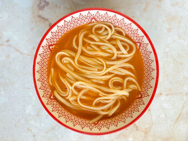 Um bowl com caldo e macarrão.