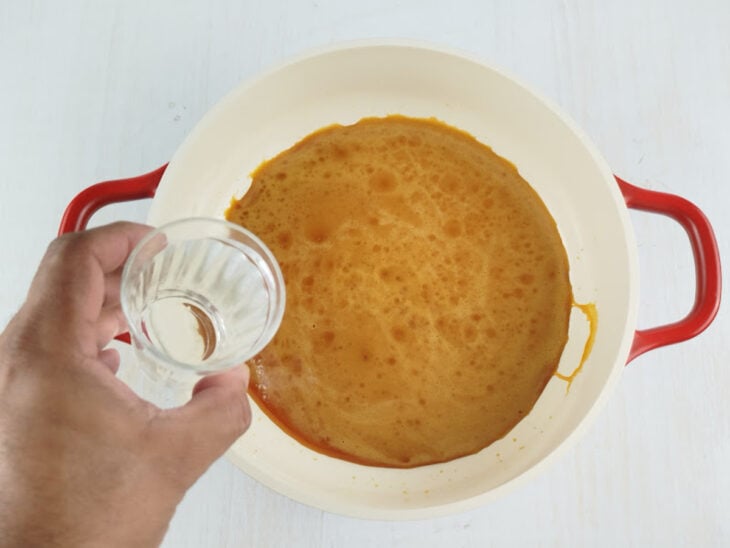 Água sendo adicionada ao caramelo enquanto a mistura é mexida para dissolver os cristais.