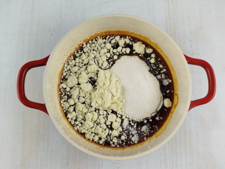 Restante do açúcar e leite em pó sendo incorporados ao caramelo ainda no fogo.