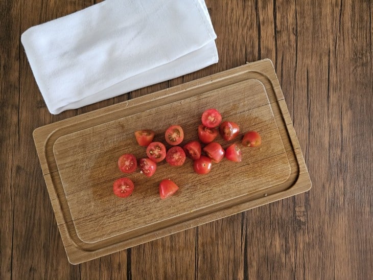 Uma tábua contendo tomates-cerejas cortados ao meio.