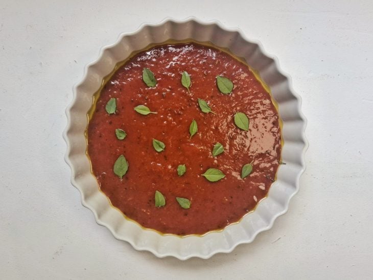 Molho de tomate com folhas de manjericão na forma.