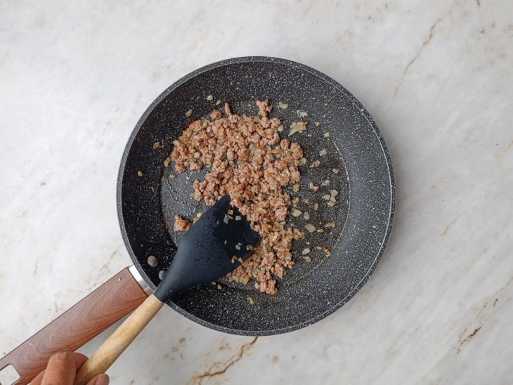 Carne moída sendo refogada até dourar levemente.