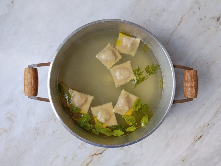 Raviolis cozinhando em água fervente aromatizada.