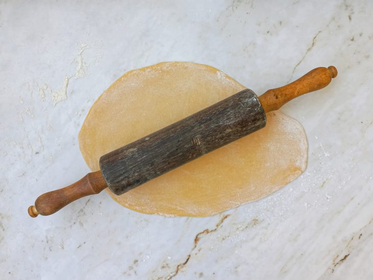 Massa aberta com rolo de madeira.