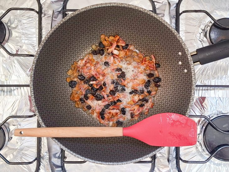 Uvas-passas sendo incorporadas ao bacon frito.