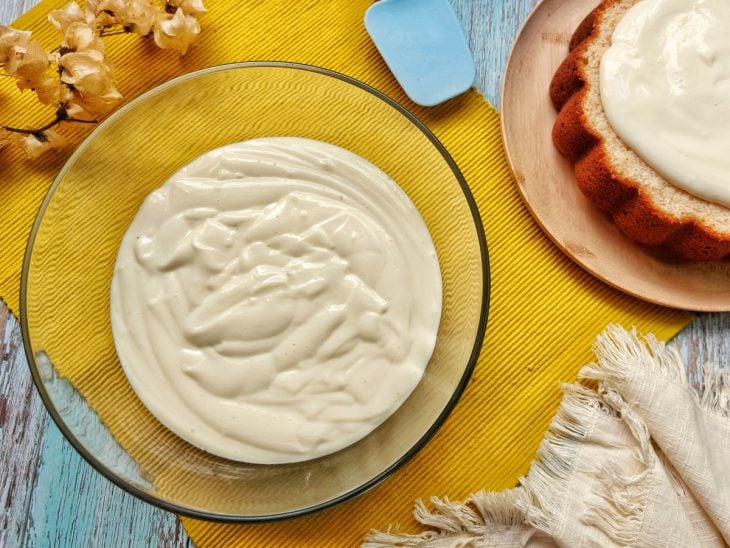 Um recipiente contendo recheio de creme branco para bolo.