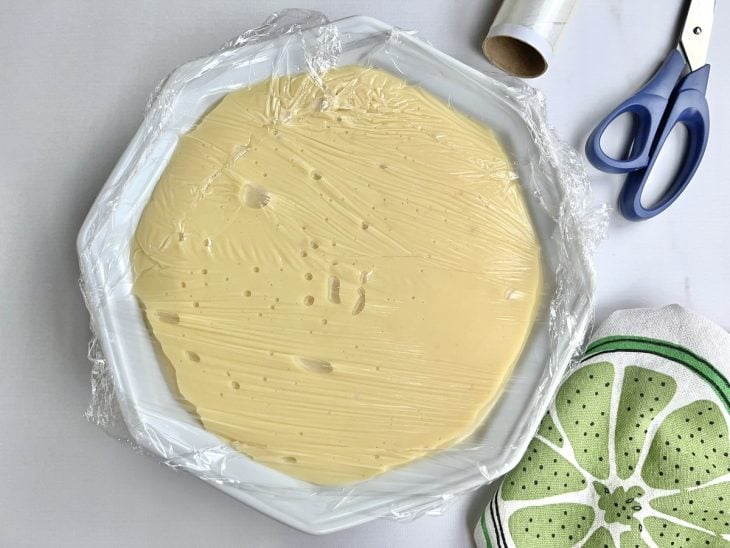 Um recipiente com o recheio de limão coberto com plástico-filme.
