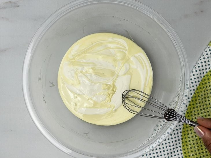 Um recipiente contendo a mistura de chocolate branco derretido e creme de leite.