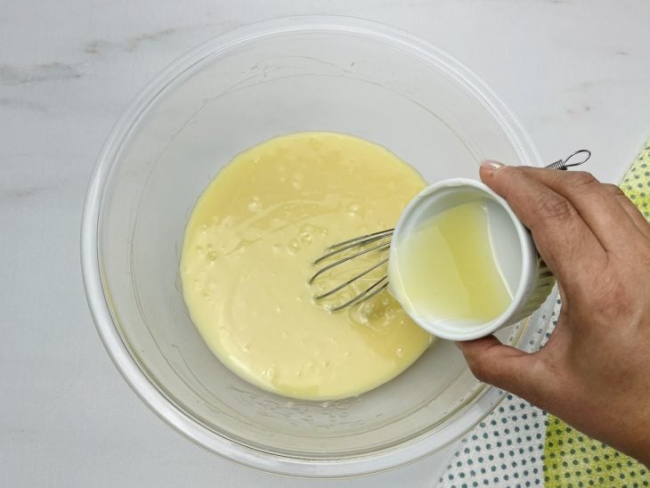 Um recipiente contendo a mistura de chocolate branco derretido, creme de leite e suco de limão.