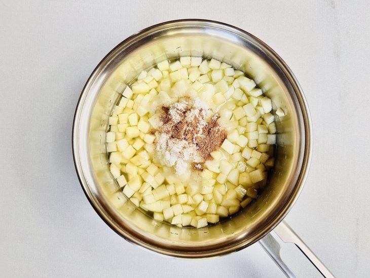 Panela com maçã, água, açúcar, canela em pó e suco de limção.