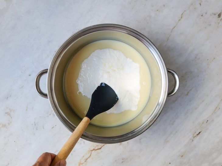 Coco em flocos e leite sendo adicionados à mistura cremosa.