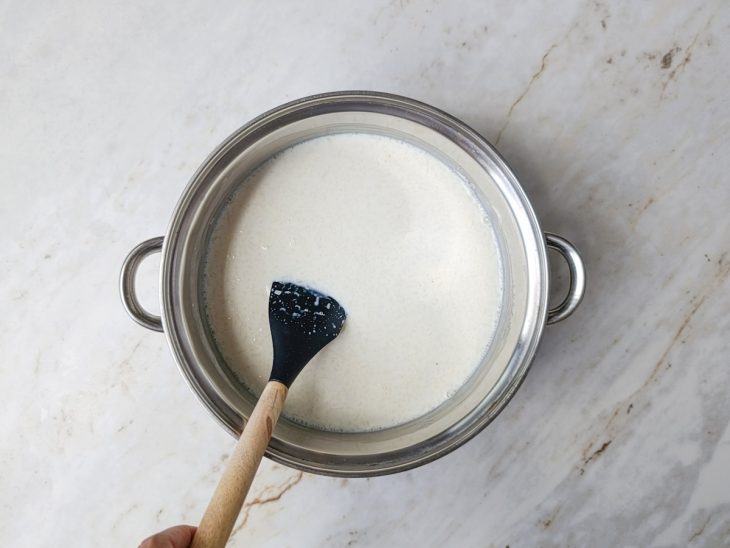 Leite condensado e creme de leite sendo misturados na panela.