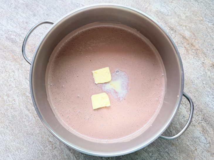 Leite condensado e manteiga sendo incorporados na panela.