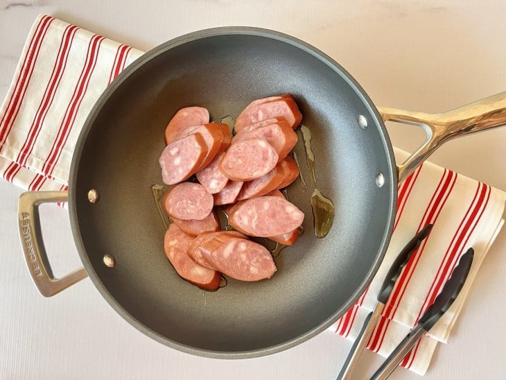 Linguiça calabresa em uma panela com um fio de óleo.